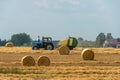 Tractor collects hay bales in the fields. A tractor with a trailer baling machine collects straw and makes round large bales for Royalty Free Stock Photo