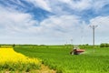 Tractor on the corn and rapeseed field with power lines and wind turbines Royalty Free Stock Photo