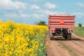 Tractor on country dirt road by the blooming rapeseed crop field Royalty Free Stock Photo