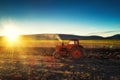 Tractor cultivating field at spring, sun sets dawn behint the hills Royalty Free Stock Photo