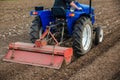 The tractor is cultivating the soil in the farm field. Freeing milling earth ground from old crops. Softening and improving soil