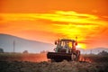 Tractor with cultivator handles field before planting, sunset