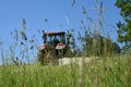The tractor cuts the grass on the meadow. Focus on grass. Royalty Free Stock Photo