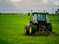 Tractor cutting grass in a sport field, Rugby goal in the background