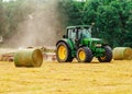 Tractor cutting hay in summer time against blue cloudy sky,  haystacks on the field Royalty Free Stock Photo