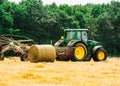 Tractor cutting hay in summer time against blue cloudy sky,  haystacks on the field Royalty Free Stock Photo