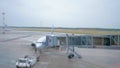 The tractor drawing near the airplane before flying and aircraft technician checking detaching of the airbridge from the