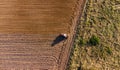 Vibrocultivator pulled by a tractor in an earthen field bordered by wild vegetation. Working the land before sowing.