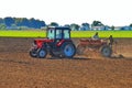 tractor drivers plow a field with a tractor. people work on a tractor seeder.