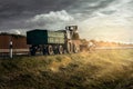 tractor behind a car truck on a country road in bright sun with sunbeams and gloomy sky Royalty Free Stock Photo