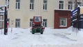 Tractor drives on the street and clears the road from snow after heavy snowfall, blizzard