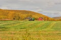 Tractor driving on grassy field with farming equiptment on overcast day in the fall