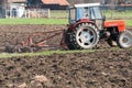 Tractor equipped with harrow working on the field