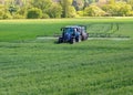 Tractor fertilizes a green field in spring