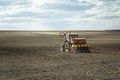 Tractor fertilizing the plowed field, horizon and sky Royalty Free Stock Photo