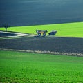 Tractor in the field in spring time. Green field in spring and work on cultivating the soil. Concept for agriculture Royalty Free Stock Photo