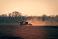 Tractor on a field in the sun with dust flying Royalty Free Stock Photo