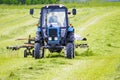 The tractor in the field with turns the hay on drying Royalty Free Stock Photo