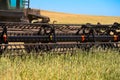 A tractor with a front reaper mows wheat ears in the field. A fragment. Close-up Royalty Free Stock Photo