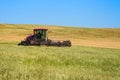 A tractor with a front reaper mows wheat in a field under wheat hay. Copy space Royalty Free Stock Photo