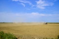 Tractor with a grader aligns the soil on the field. The tractor raised dust.