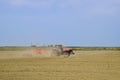 Tractor with a grader aligns the soil on the field. The tractor raised dust.