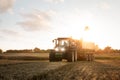 Tractor with a grain cart on a field at dusk