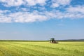 Tractor in green field under blue sky with clouds Royalty Free Stock Photo