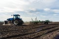 A tractor with seedbed cultivator ploughs field on morning