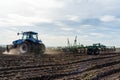 A tractor with seedbed cultivator ploughs field on morning