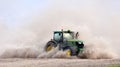 The tractor harrows the field in a huge dust cloud. Royalty Free Stock Photo