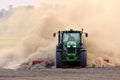 The tractor harrows the field in a huge dust cloud. Royalty Free Stock Photo