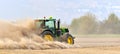 The tractor harrows the field in a huge dust cloud.