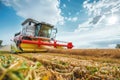 Tractor Harvesting Golden Wheat Field Under Blue Sky and White Clouds Royalty Free Stock Photo