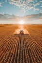 A tractor harvests corn in a field at sunset, with a bright orange sky and puffy clouds Royalty Free Stock Photo