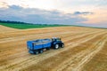 A tractor hauling a trailer cruises across a harvested field Royalty Free Stock Photo