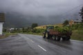 A tractor hauls freshly cut crops and transports them towards the village of Innvik during a rainy summer day Royalty Free Stock Photo