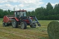 Tractor making hay bales  for livestock during field work on a farm Royalty Free Stock Photo