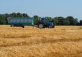 Tractor with a heavy trailer in a freshly cut hay field on a summer day Royalty Free Stock Photo