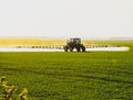 tractor with the help of a sprayer liquid fertilizers on young wheat in the field Royalty Free Stock Photo