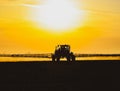 Tractor with the help of a sprayer  liquid fertilizers on young wheat in the field Royalty Free Stock Photo