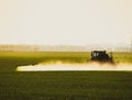 tractor with the help of a sprayer liquid fertilizers on young wheat in the field Royalty Free Stock Photo