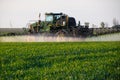 tractor with the help of a sprayer sprays liquid fertilizers on young wheat in the field Royalty Free Stock Photo