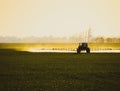 tractor with the help of a sprayer liquid fertilizers on young wheat in the field Royalty Free Stock Photo