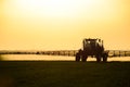 tractor with the help of a sprayer sprays liquid fertilizers on young wheat in the field Royalty Free Stock Photo