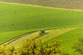 Tractor on a large green field with mowed lawn stripes. It is a sunny spring day in Czech Republic