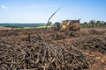 A tractor with a lifting claw loading a truck with sugar cane