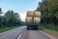 tractor loaded with several straw bales drives over a country road