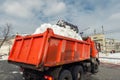 Tractor loader machine uploading dirty snow into dump truck. Cleaning city street, removing snow and ice after heavy Royalty Free Stock Photo