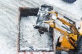 Tractor loader machine uploading dirty snow into dump truck. Cleaning city street, removing snow and ice after heavy Royalty Free Stock Photo